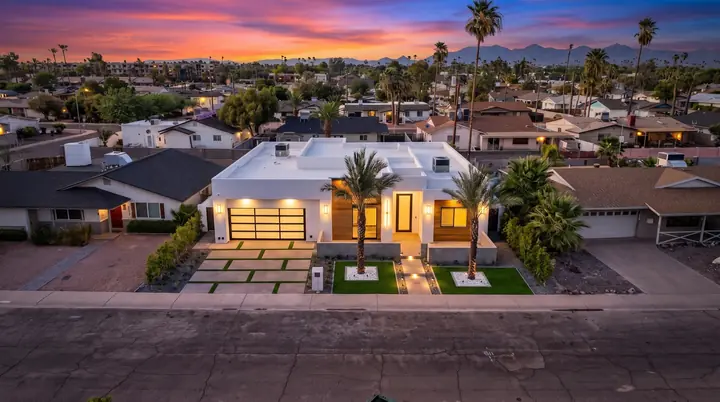 Drone view of a lit home at dusk with mountains behind